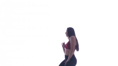 Genç ve güzel bir kız beyaz arka planda modern dans ediyor, plastikleri soyuyor.