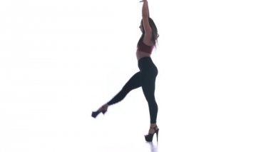 Genç ve güzel bir kız beyaz arka planda modern dans ediyor, plastikleri soyuyor.