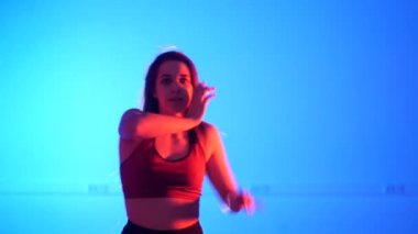 Genç, güzel bir kadın dans ediyor mavi arka planda modern dans, striptiz dansı, Vogue