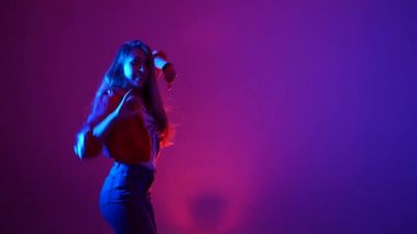 Genç, güzel bir kadın hip hop yapıyor, stüdyoda dans ediyor, mor bir arka planda, izole edilmiş.