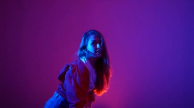 Genç, güzel bir kadın hip hop yapıyor, stüdyoda dans ediyor, mor bir arka planda, izole edilmiş.