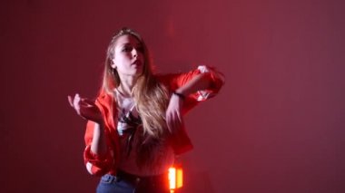 Genç ve güzel bir kadın hip hop yapıyor, stüdyoda dans ediyor, kırmızı arka planda, izole bir şekilde.