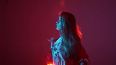 Genç ve güzel bir kadın hip hop yapıyor, stüdyoda dans ediyor, kırmızı arka planda, izole bir şekilde.