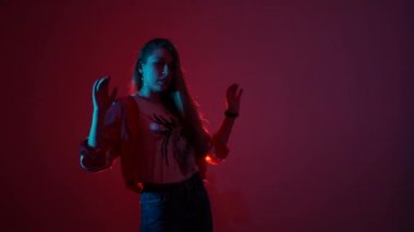 Genç ve güzel bir kadın hip hop yapıyor, stüdyoda dans ediyor, kırmızı arka planda, izole bir şekilde.