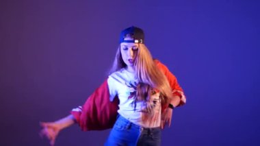 Beyzbol şapkalı güzel bir kız hip hop yapıyor, stüdyoda mor bir arka planda sokak dansı yapıyor, izole edilmiş.