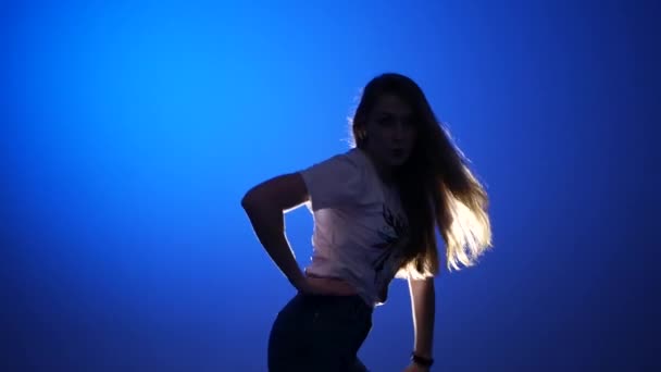 若い美しい女性がヒップホップを踊りスタジオで青い背景でストリートダンスを踊り孤立した — ストック動画