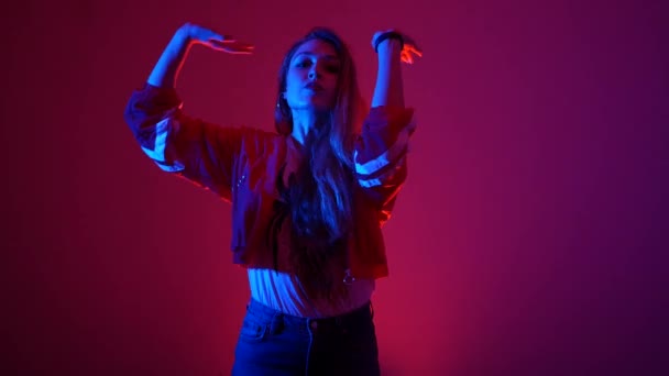 若い美しい女性がヒップホップを踊りスタジオで赤い背景でストリートダンスを踊り孤立した — ストック動画