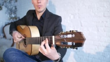 beyaz tuğla duvara karşı bir akustik gitar flamenko müzik çalan gitarist, saç modeli üst düğüm