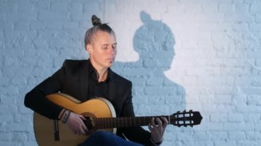 gitarist beyaz bir tuğla duvara karşı bir akustik gitar flamenko çalış, gölge onun hareketlerini tekrarlar