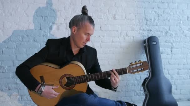 白レンガの壁の背景にフラメンコ音楽を演奏するギタープレーヤー ギターケース — ストック動画