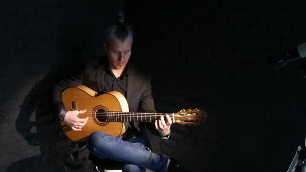 黒レンガの壁の背景にフラメンコ音楽を演奏ギタープレーヤー — ストック動画
