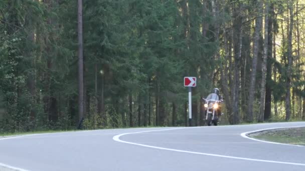 ヘルメットの男性バイカーは 日没時に森林道路に沿ってオートバイに乗ります — ストック動画