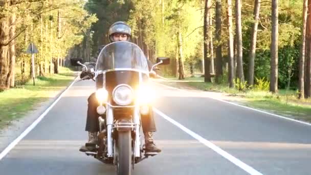 ヘルメットの男性バイカーは 日没時に森林道路に沿ってオートバイに乗ります — ストック動画