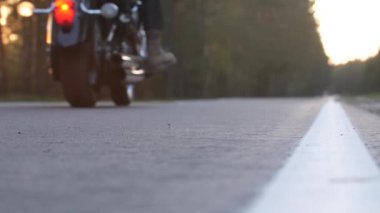 kask olmadan yetişkin bisikletçi gün batımında bir orman yolu boyunca bir motosiklet sürmek 