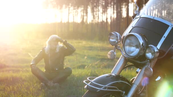 Дорослий Чоловік Довгим Сивим Волоссям Сидить Траві Біля Мотоцикла Заході — стокове відео