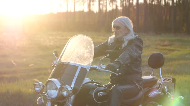 Dorosły Człowiek Długimi Szarymi Włosami Siedzi Motocyklu Zachodzie Słońca — Wideo stockowe