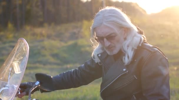 Uzun Gri Saçlı Yetişkin Adam Portresi Gün Batımında Bir Motosiklet — Stok video
