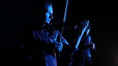 siyah arka plan üzerinde elektrikli viyolonsel ve elektrik keman çalan genç müzisyenlerin düet, izole