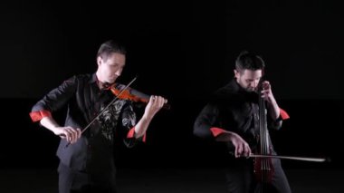 siyah bir arka plan üzerinde elektrikli viyolonsel ve elektrik keman çalan genç erkeklerin düet, izole