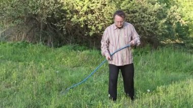 adam bir tırpan kullanarak çim mows