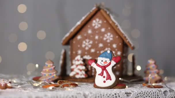 Handgemachtes Lebkuchenhaus Vor Dem Hintergrund Funkelnder Lichter Schneemannfiguren Und Eines — Stockvideo