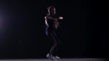 Afrika örgülü güzel bir kız hip hop yapıyor, stüdyoda siyah bir arka planda sokak dansı yapıyor, izole edilmiş.