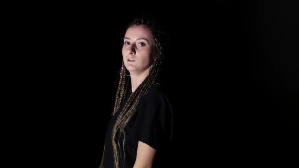 Jeune belle fille avec des tresses africaines dansant hip hop, danse de rue en studio sur fond noir, isolée 