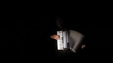 adam müzisyen ustaca siyah bir arka planda stüdyoda akordeon oynar, el ve anahtarlar yakın çekim, izole