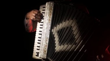 adam müzisyen ustaca siyah bir arka planda stüdyoda akordeon oynar, el ve anahtarlar yakın çekim, izole