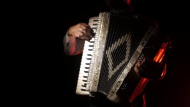 adam müzisyen ustaca siyah bir arka planda stüdyoda akordeon oynar, el ve anahtarlar yakın çekim, izole
