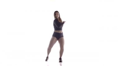 Uzun saçlı, uzun saçlı, genç, şehvetli bir dansçı kız. Tayt ve şortla dans ediyor. Dans pisti twerk dansı, modern dans, kalçalarını sallıyor.