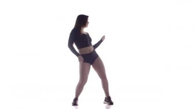 Uzun saçlı, uzun saçlı, seksi bir kadın dansçı. Tayt ve şortla dans ediyor. Dans pisti twerk 'i, modern dans, kalçalarını sallıyor.