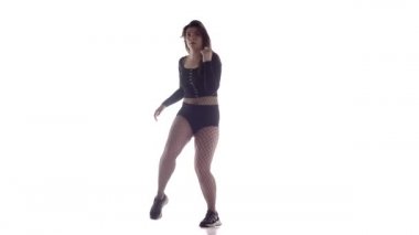 Uzun saçlı, uzun saçlı, seksi bir kadın dansçı. Tayt ve şortla dans ediyor. Dans pisti twerk 'i, modern dans, kalçalarını sallıyor.