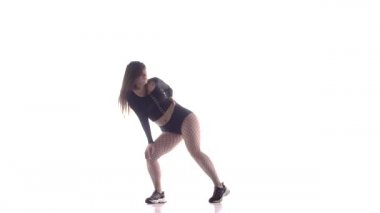 Uzun saçlı, uzun saçlı, seksi bir kadın dansçı. Tayt ve şortla dans ediyor. Dans pisti twerk 'i, modern dans, kalçalarını sallıyor.