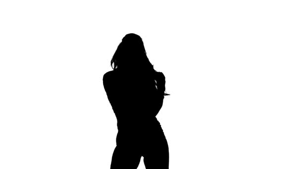 白の背景に黒のシルエット 若い官能的な美しい女の子のダンサーとともに長い髪でフィッシュネットタイツとショートパンツ精力的にダンスホールトーク ストリートモダンダンス 彼女のお尻を振る スローモーション 中長期ショット — ストック動画