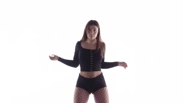 Plan moyen long de jeune danseuse sensuelle belle fille aux cheveux longs en collants et shorts résille dansant vigoureusement dancehall twerk, danse moderne de rue, secouant ses fesses, isolée, au ralenti 