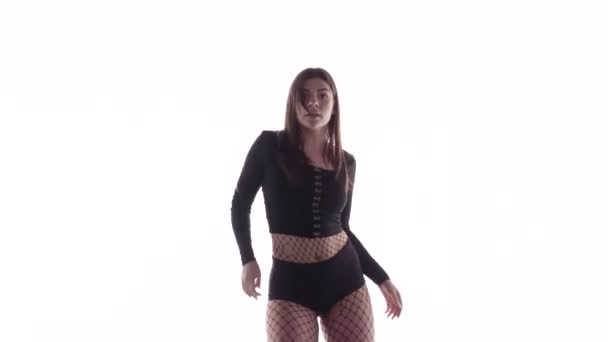 Plan moyen long de jeune danseuse sensuelle aux cheveux longs en collants et shorts résille dansant vigoureusement dancehall twerk, street modern dance, secouant ses fesses, isolée, au ralenti 