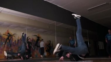 Spor salonunda ağır çekimde yel değirmeni yapıp dans eden genç bir adam. Break dans tekniğini geliştirme kavramı. Gençlik alt kültürü. Çağdaş koreografi