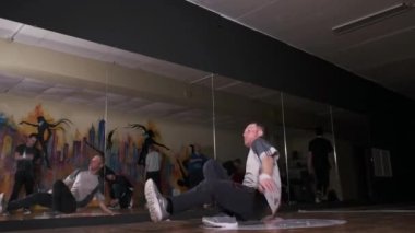 Spor salonunda ağır çekimde yel değirmeni yapıp dans eden genç bir adam. Break dans tekniğini geliştirme kavramı. Gençlik alt kültürü. Çağdaş koreografi