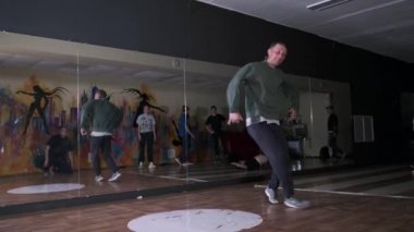 Spor salonunda ağır çekimde yel değirmeni yapıp dans eden genç bir adam. Break dans tekniğini geliştirme kavramı. Gençlik alt kültürü. Çağdaş koreografi