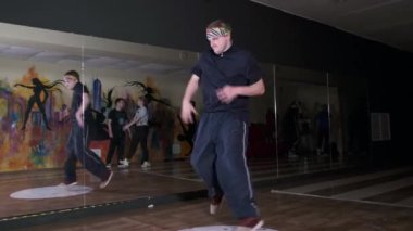 Aktif bir gencin hip hop koreografisi ve break dansı videosu. Diğer dansçılar yakınlarda duruyor. Dans okulu. Break dans tekniğini geliştirme kavramı. Gençlik alt kültürü. Çağdaş koreografi. Yavaş çekim 