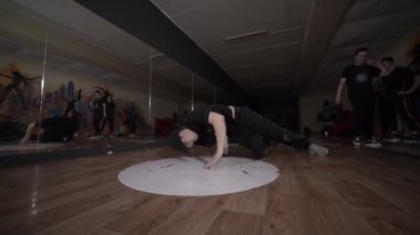 Spor salonunda ağır çekimde yel değirmeni yapıp dans eden genç bir adam. Break dans tekniğini geliştirme kavramı. Gençlik alt kültürü. Çağdaş koreografi
