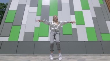 Genç kız dans ediyor ve modern koreografi yapıyor, sokak dansı yapıyor, poz veriyor, sokak tarzı kıyafetlerle serbest dans ediyor. Düşük atış noktası. Yavaş çekim