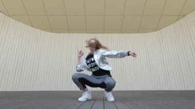 Güzel kız halk parkında dans edip modern koreografi sokak dansı yapıyor. Gençlik alt kültürü. Düşük atış noktası. Yavaş çekim