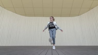 Güzel kız halk parkında dans edip modern koreografi sokak dansı yapıyor. Gençlik alt kültürü. Düşük atış noktası. Yavaş çekim