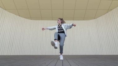 Güzel kız halk parkında dans edip modern koreografi sokak dansı yapıyor. Gençlik alt kültürü. Düşük atış noktası. Yavaş çekim