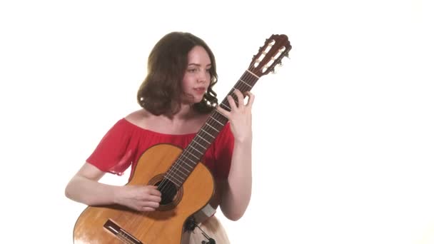 穿着红色衬衫的年轻女音乐家弹古典吉他 中远距离射击 穿上衣服被隔离了 — 图库视频影像