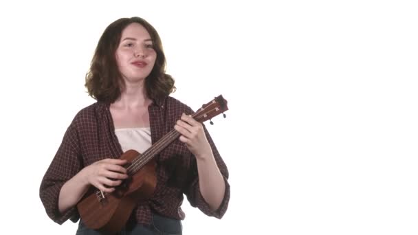 Ung Flicka Musiker Rutig Skjorta Spelar Ukulele Framför Rampljuset Isolerad — Stockvideo