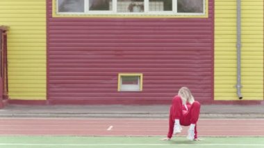 Eşofmanlı, uzun saçlı, enerjik genç bir kadın modern sokak dansı yapıyor, hip hop duvara dayanıyor. Gençlik alt kültürü. Çağdaş koreografi. Yavaş çekim