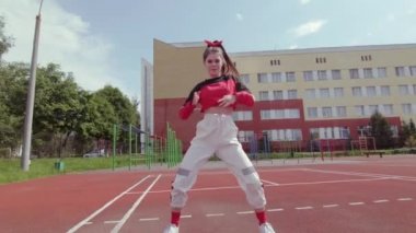 Güzel kız dans ediyor ve modern koreografi yapıyor, sokak dansı yapıyor, poz veriyor, sokak tarzı kıyafetlerle serbest dans ediyor. Gimbal atışı. Yavaş çekim
